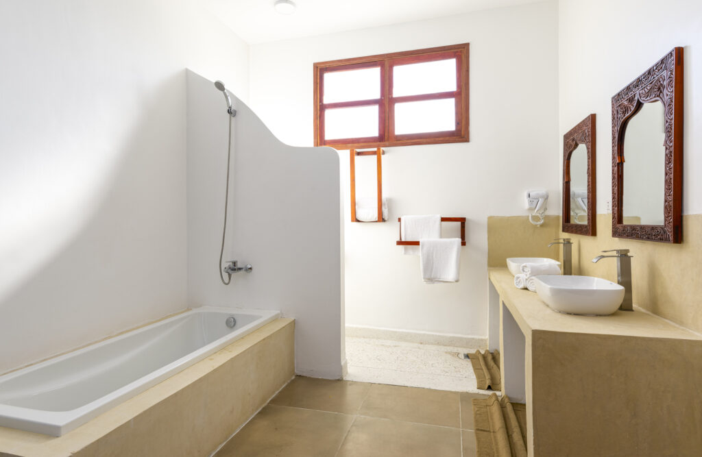 Simple shower with bathtub and two sinks in a bathroom at Tasneem Hotel Zanzibar